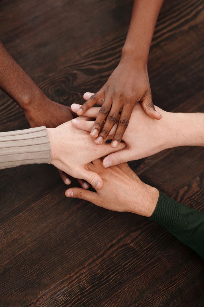 Crafting Captivating Headlines: Your awesome post title goes here Close-up of diverse hands stacked together on wooden surface symbolizing teamwork and unity.