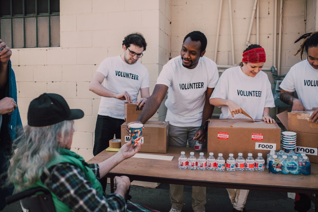 About Volunteers distribute food and drinks to the needy at an outdoor charity event.