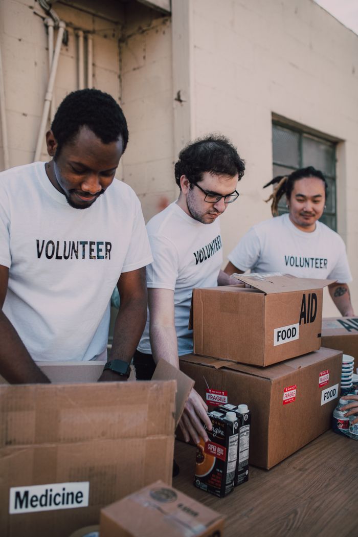 Services Group of volunteers preparing food and medicine boxes for charity distribution.